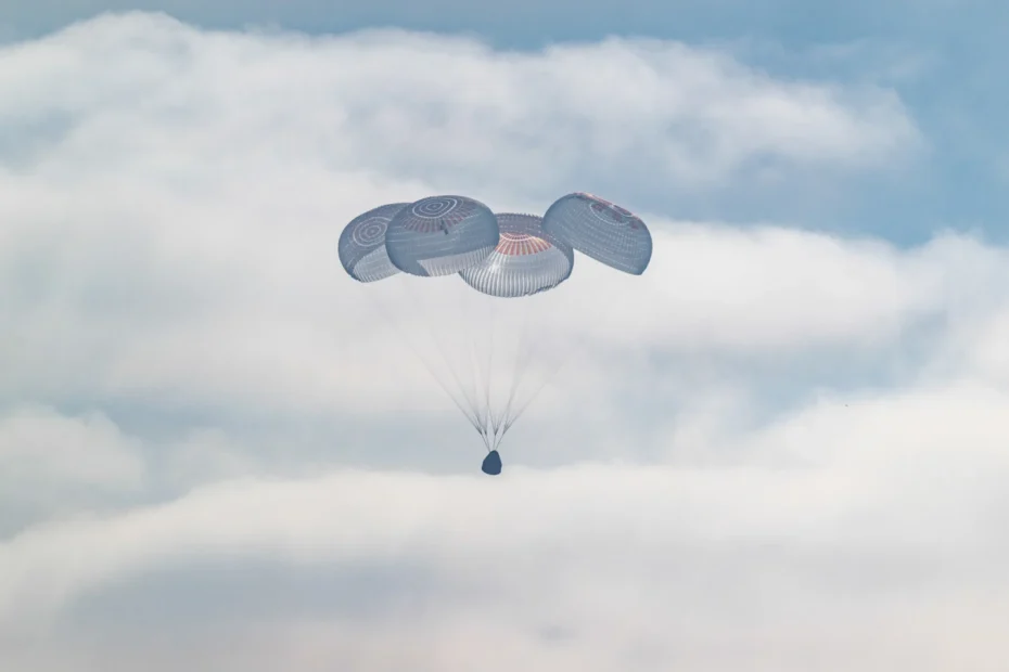 La cápsula Crew Dragon Freedom desciende con sus cuatro paracaídas sobre las nubes, antes de amerizar frente a Los Ángeles