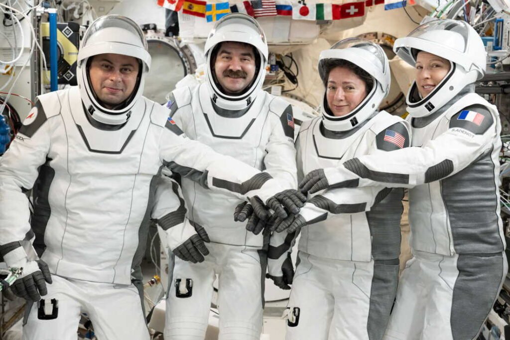 Los cuatro integrantes de la Crew-12, con los trajes presurizados de la Dragon puestos, apilan las manos a bordo de la Estación Espacial Internacional