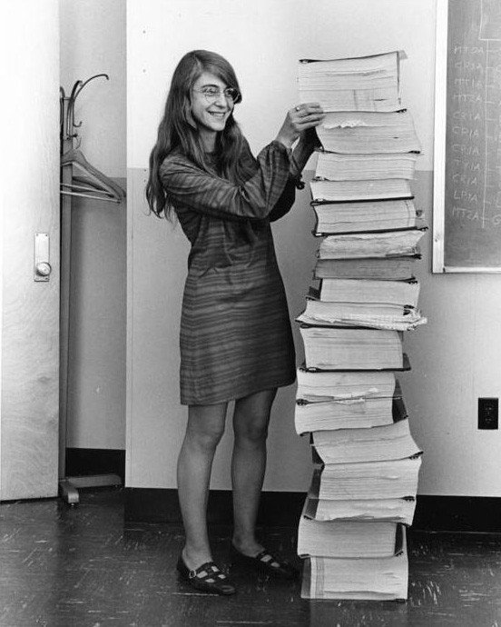 Margaret Hamilton, en 1969, junto a una pila de listados con el código del software del Apolo, casi tan alta como ella
